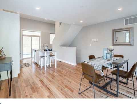 A dining room with a table set for two and a kitchen area in the background.
