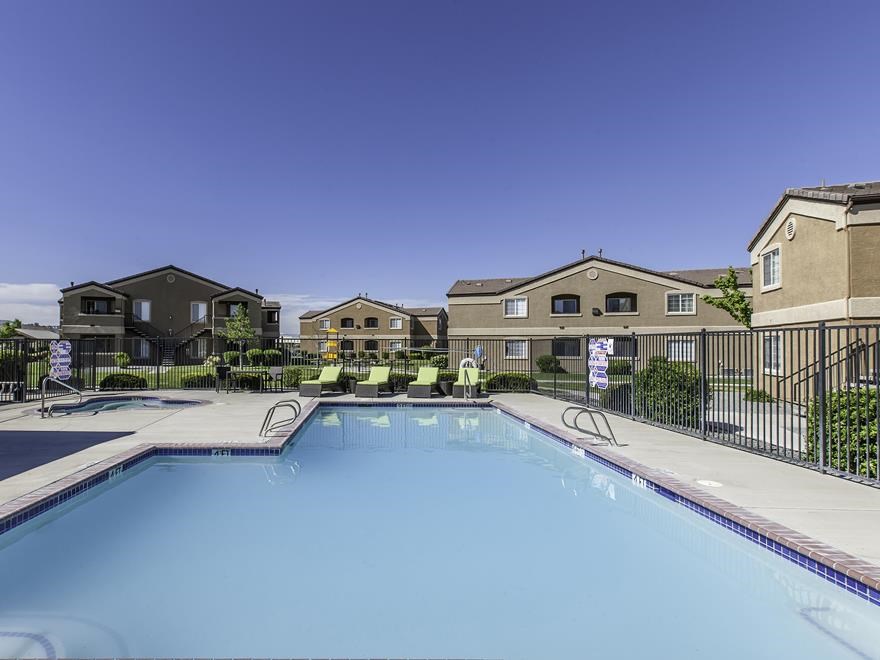 a swimming pool with chairs in front of apartment buildings