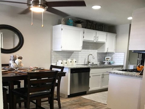 a kitchen with white cabinets and a table and chairs