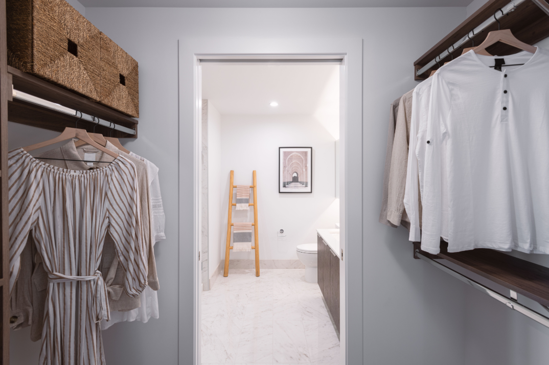 a closet with clothes and a ladder in a bathroom