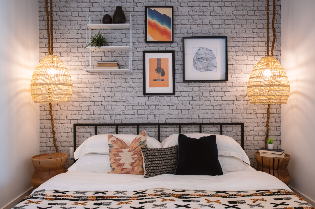 a bedroom with a bed with pillows and pictures on a brick wall