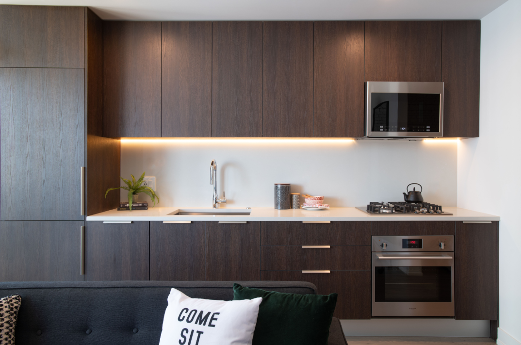 a kitchen with wooden cabinets and a black couch