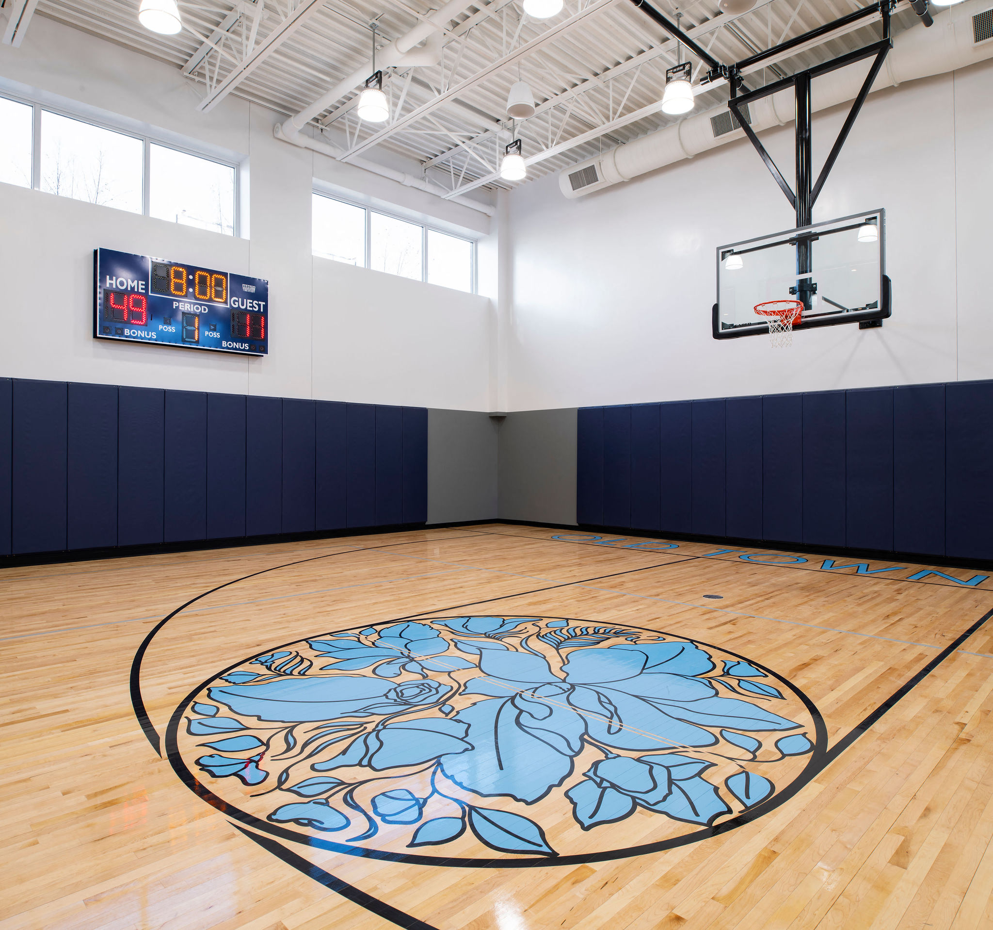 a basketball court in a gym with a blue mural on the floor