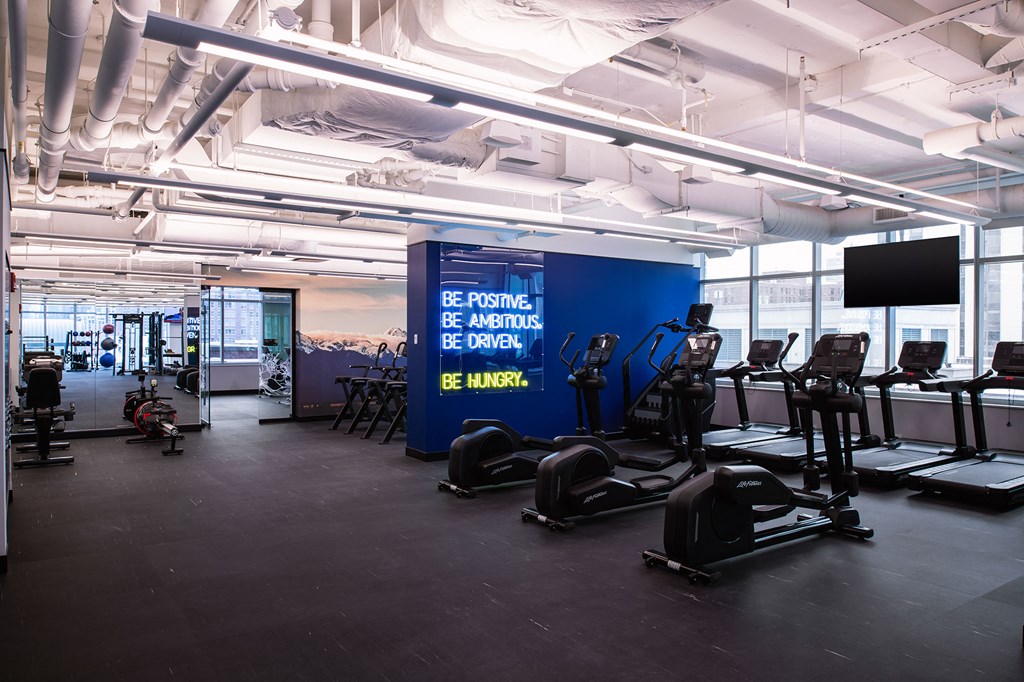a gym with cardio machines and a wall with a banner
