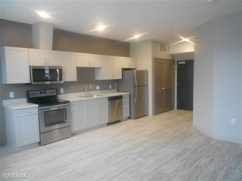 an empty kitchen with white cabinets and stainless steel appliances
