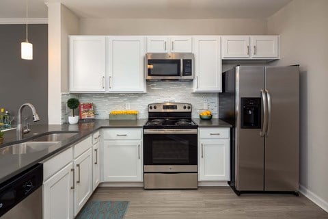 A modern kitchen with white cabinets and stainless steel appliances.
