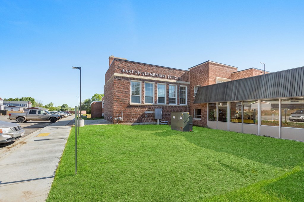 the front of the elementary school with a green lawn and a parking lot