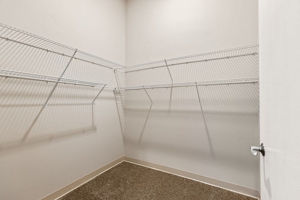 the spacious closets in the master bedroom of a home with white walls and shelves