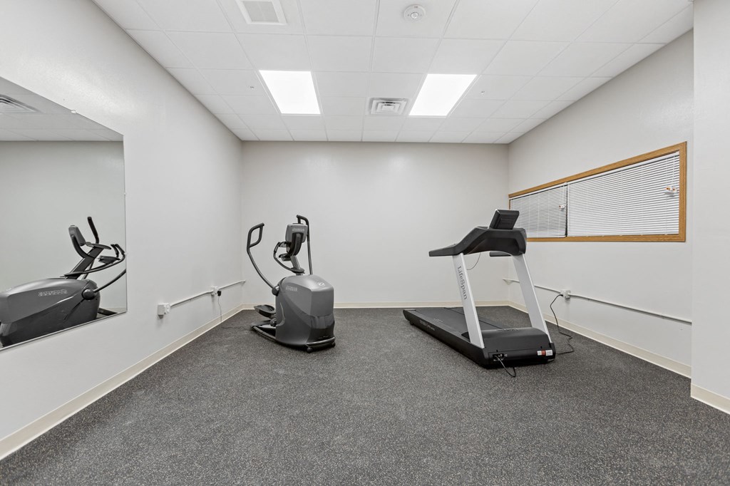 two exercise machines in an empty gym room