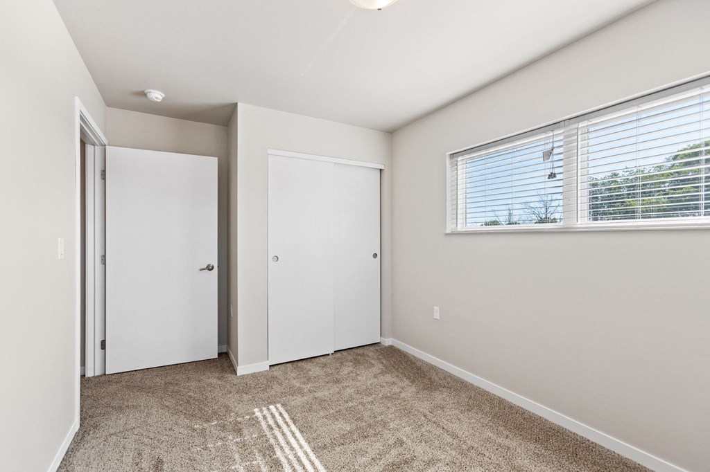 a bedroom with a large window and a door to a closet