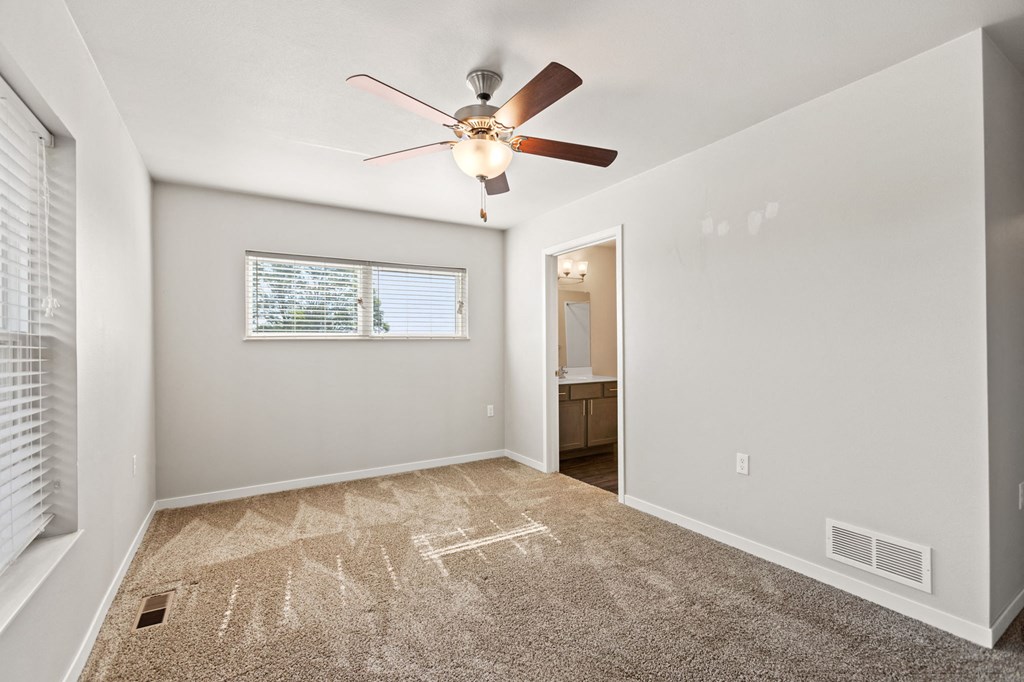 an empty room with a ceiling fan and a window