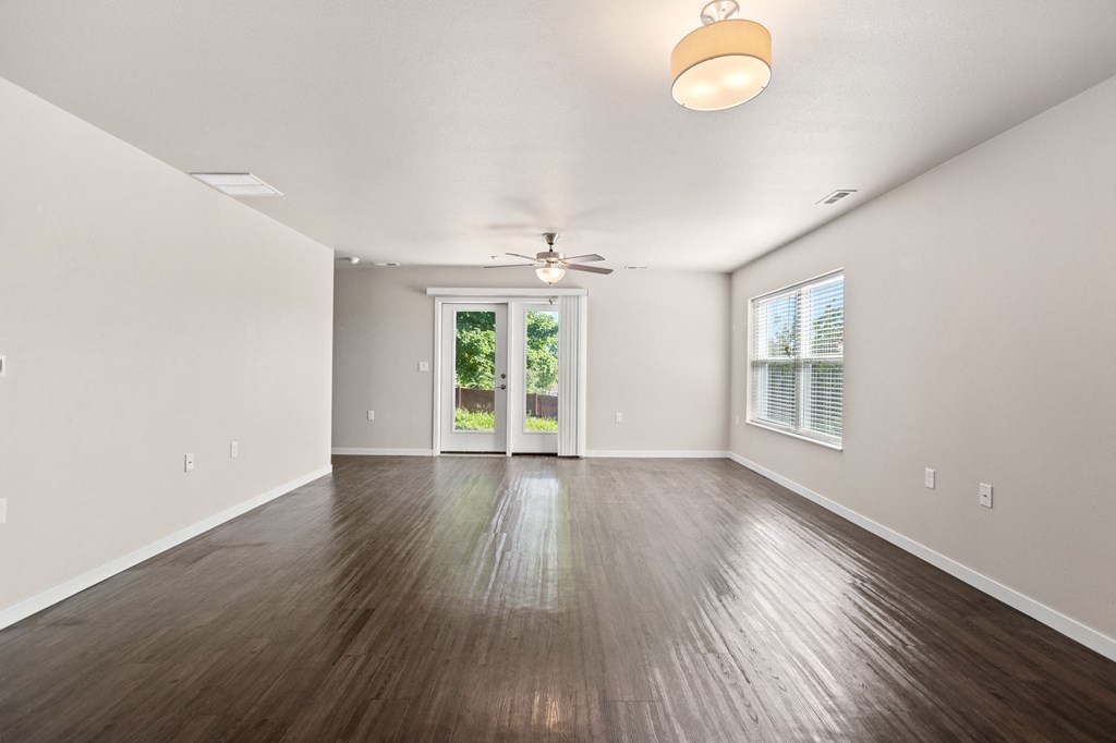 an empty living room with hardwood floors and a ceiling fan
