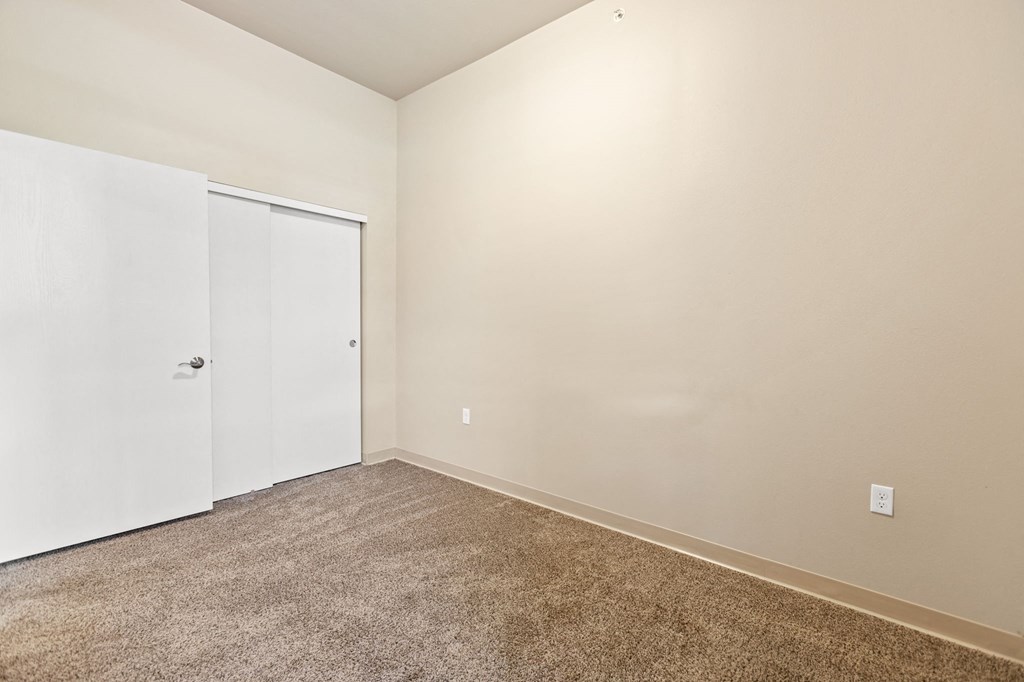 a bedroom with white walls and carpet and a door