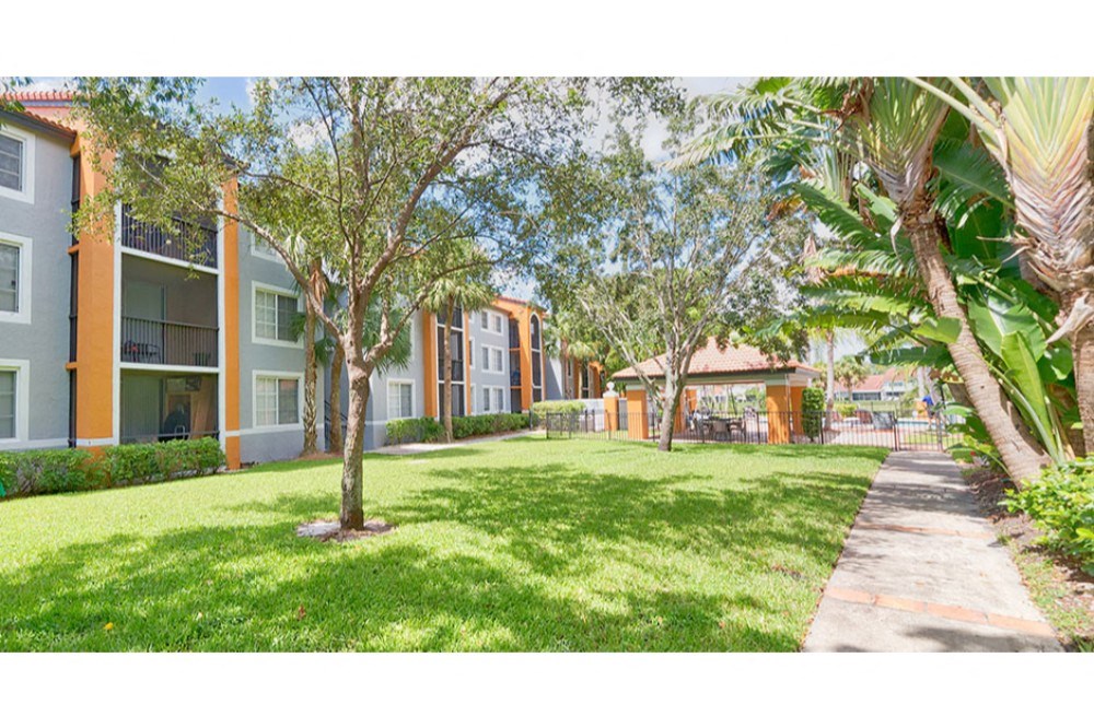 a view of the grass outside of an apartment building