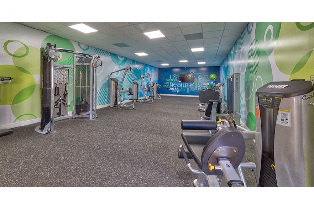 a gym with exercise equipment and walls covered in graffiti