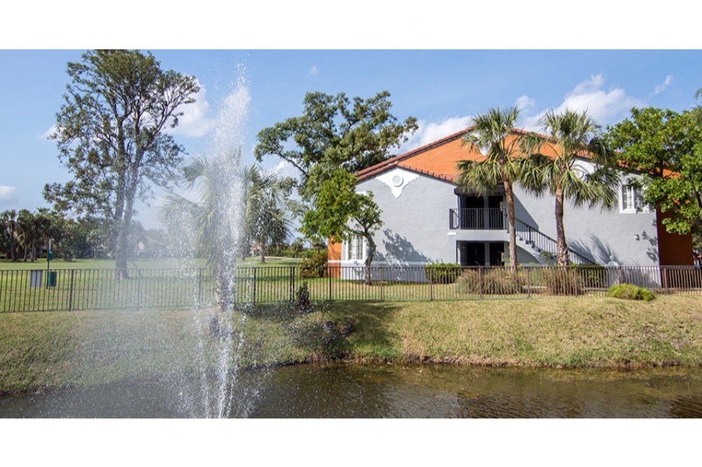 a fountain in a pond in front of a house