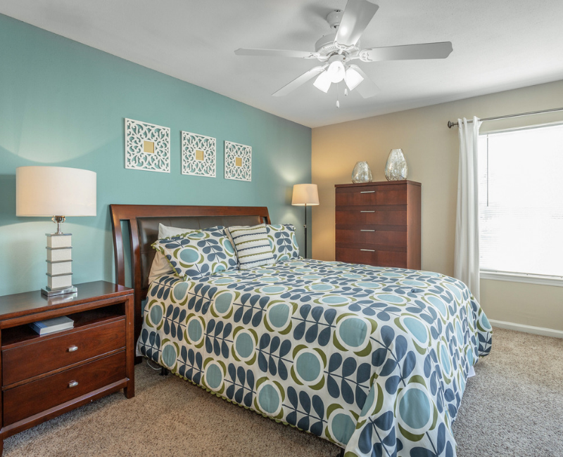 Spacious bedroom with plush carpeting, ceiling fan, and large windows at Preakness Apartments