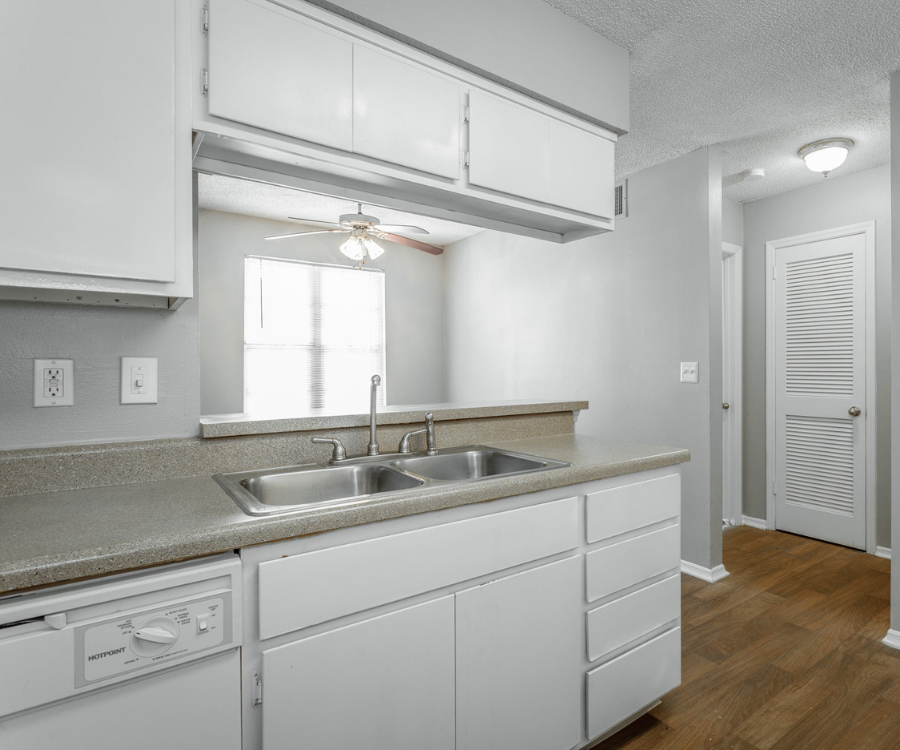 a kitchen with white cabinets and a sink and a ceiling fan