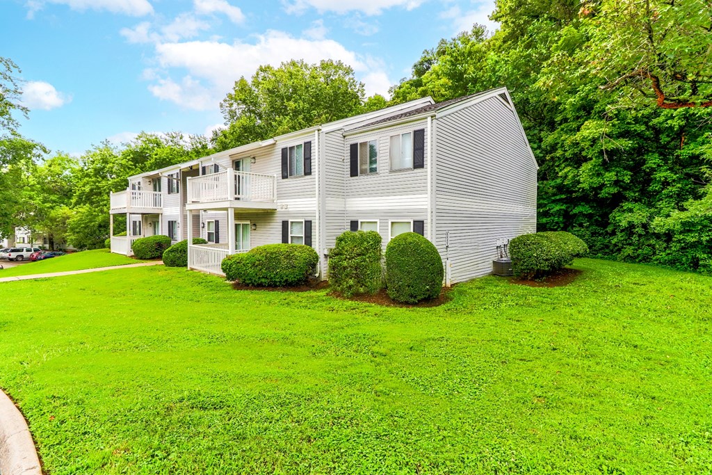 a white house on a green lawn with trees