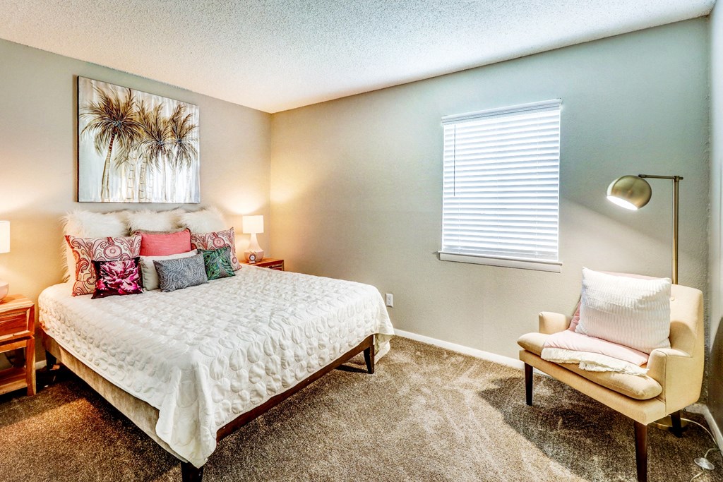 a bedroom with a bed and a chair and a window