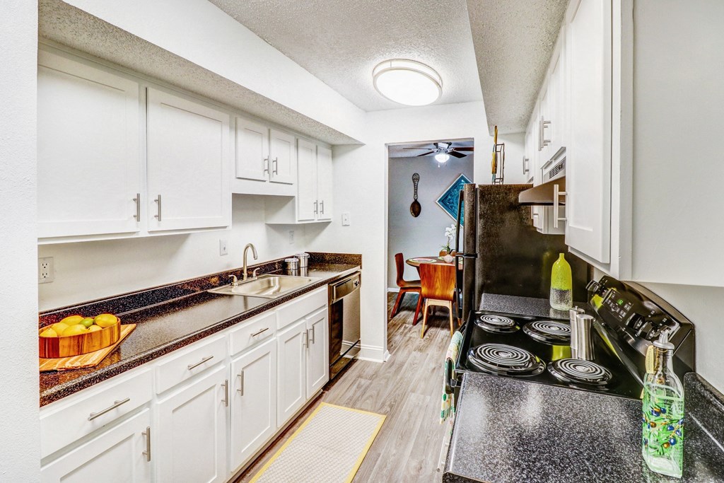 a kitchen with white cabinets and black counter tops