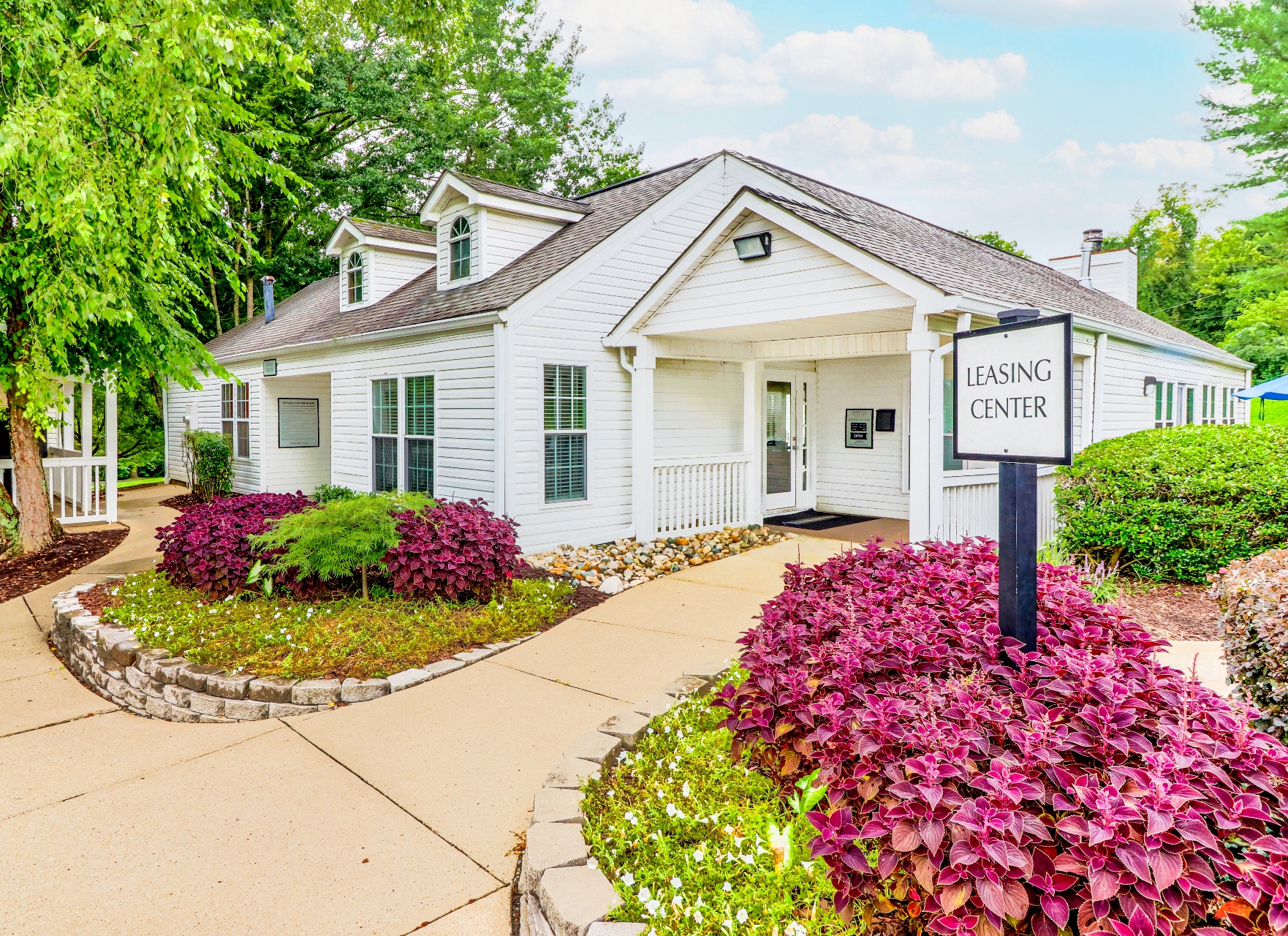 a white house with a leasing center sign in front of it