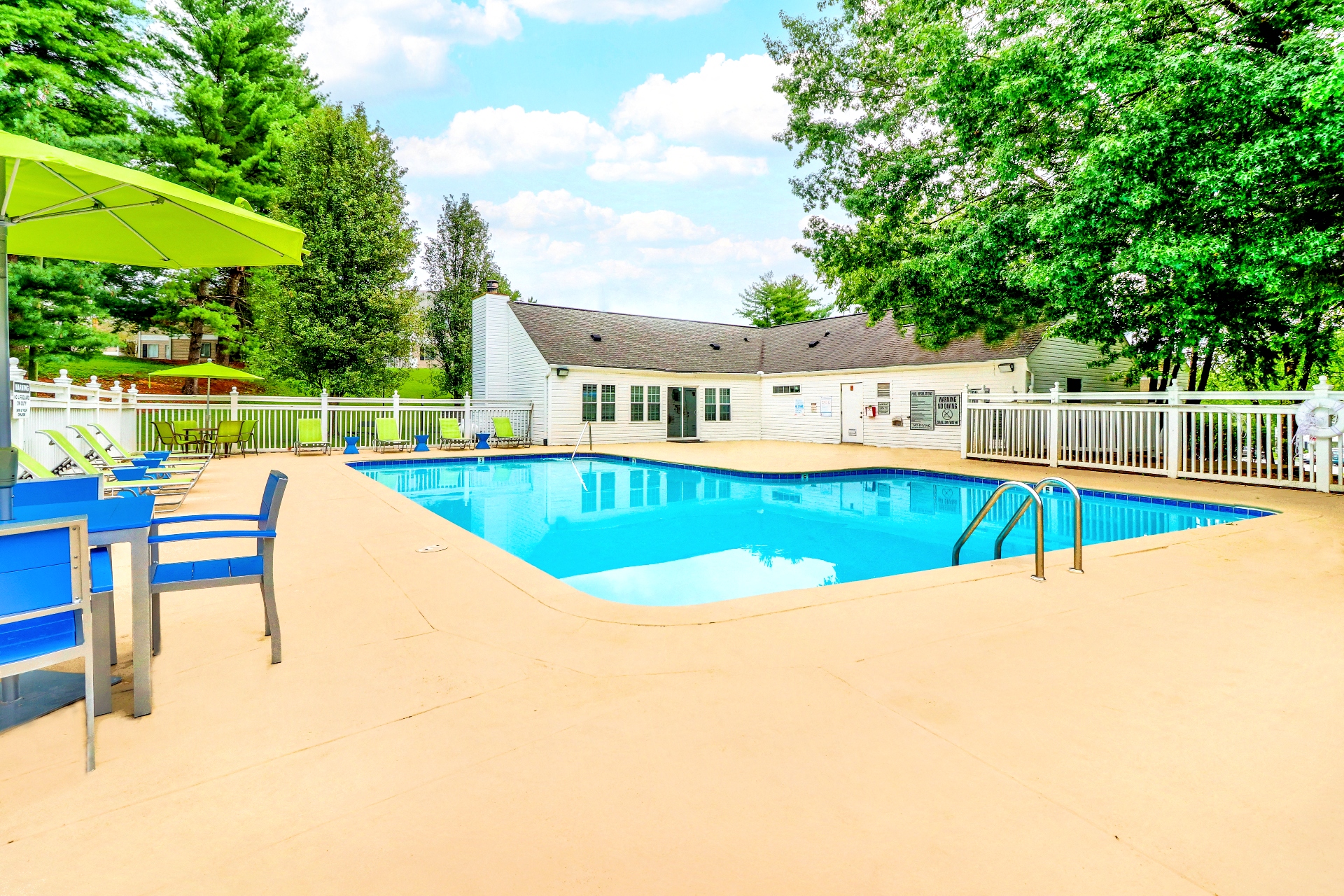 our resort style swimming pool is surrounded by chairs and tables