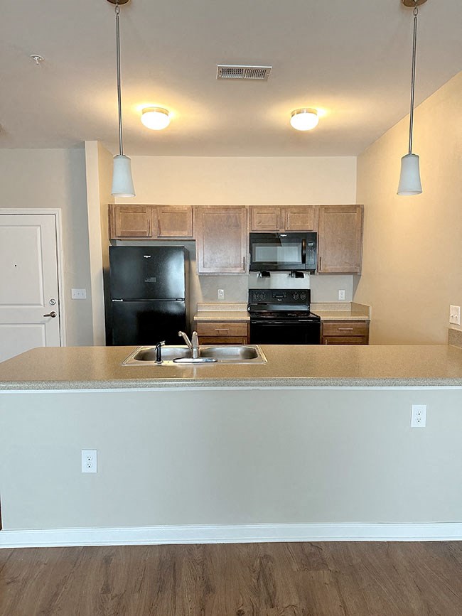 A kitchen with a black fridge and stove top oven.