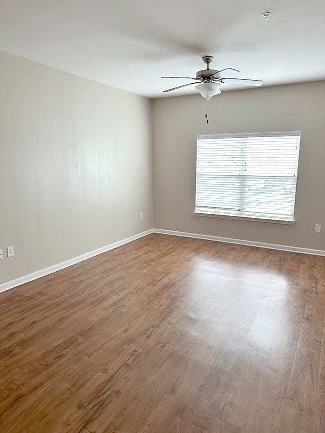 A room with a ceiling fan and a window with blinds.