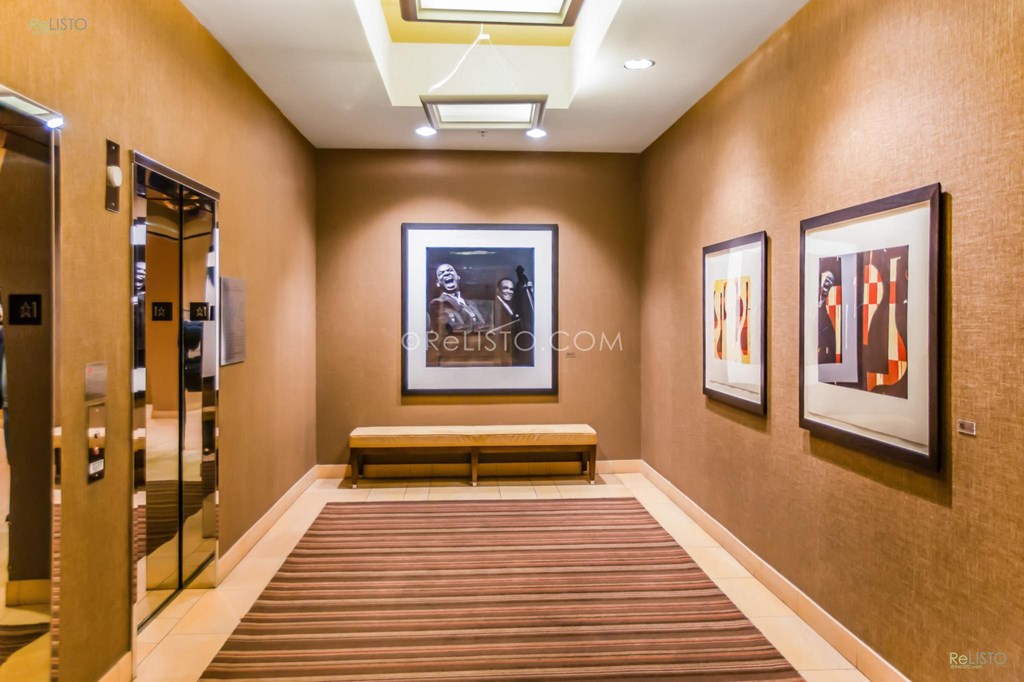 a long hallway with a painting on the wall and a bench