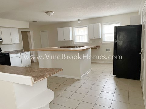 A kitchen with white cabinets and a black refrigerator.
