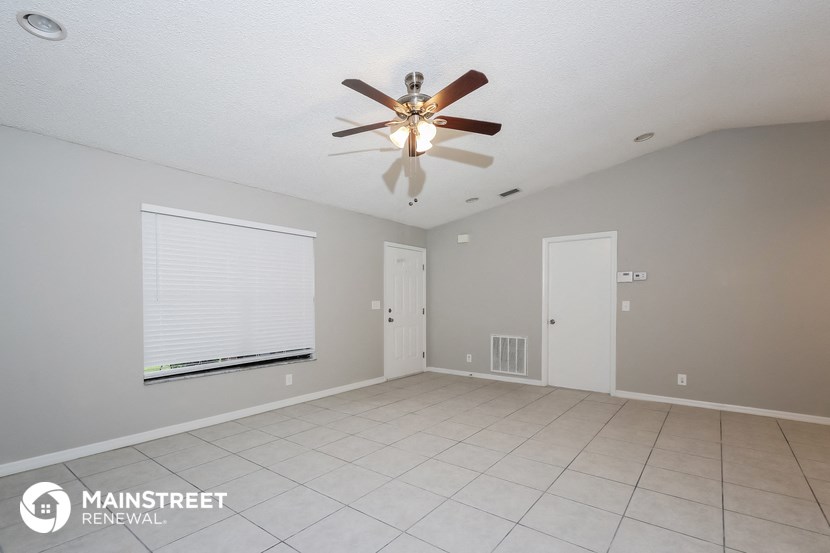 the spacious living room with ceiling fan and tile flooring