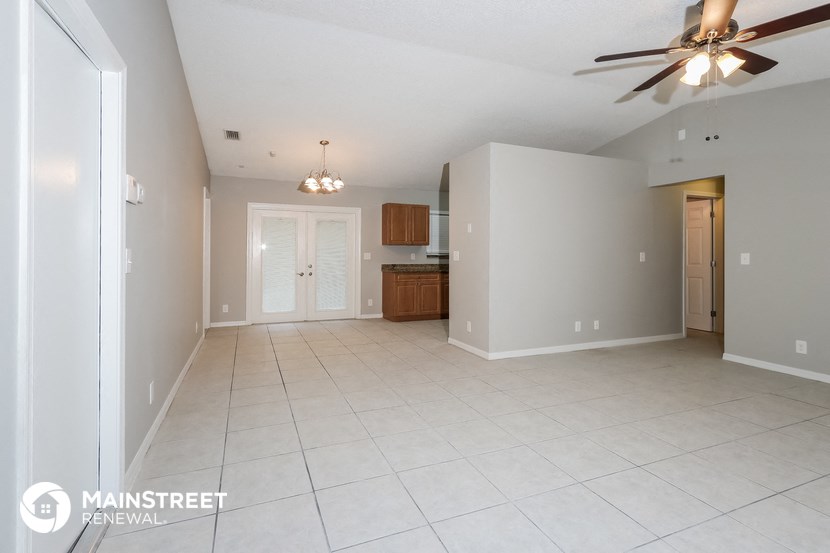 a spacious living room with white tile flooring and a ceiling fan