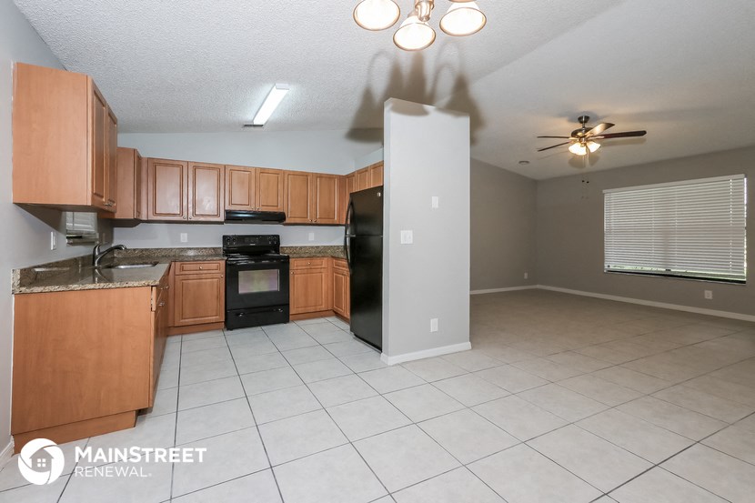 a kitchen with wooden cabinets and black appliances and a white tile floor