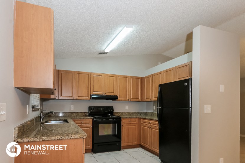 a kitchen with wooden cabinets and a black refrigerator