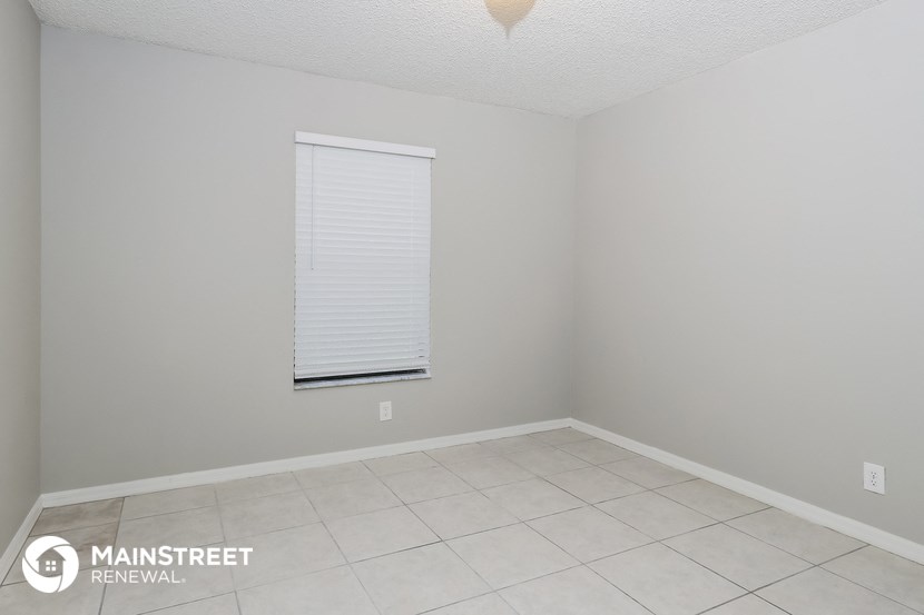 the interior of an empty room with a white tile floor and a window with an
