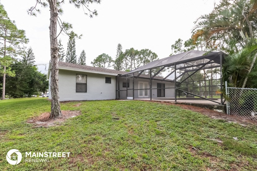 a white house with a greenhouse and a grass yard