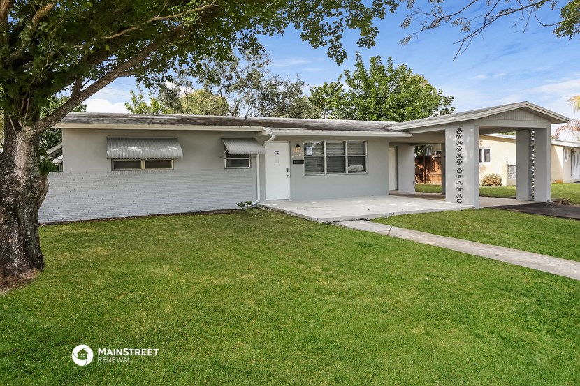a white house with a lawn and a tree