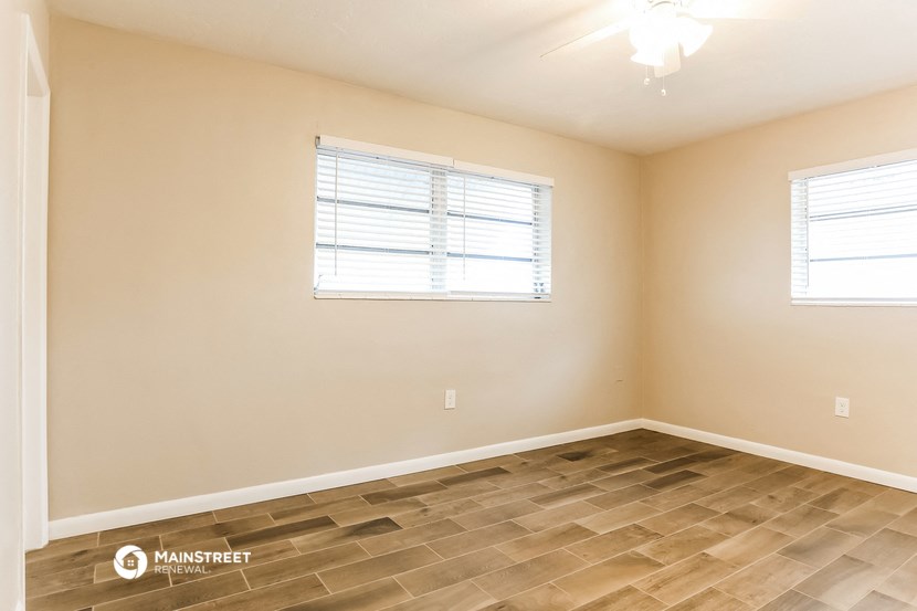 the spacious living room with wood flooring and a window