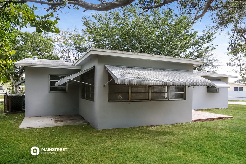 a small white house with a yard and a tree