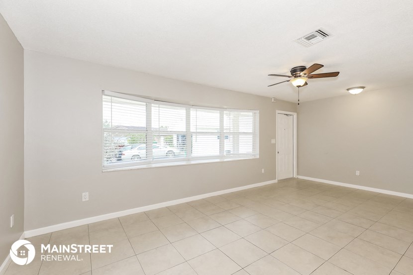 an empty living room with a ceiling fan and a large window
