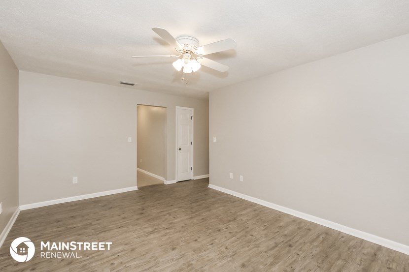 the spacious living room with ceiling fan and wood flooring