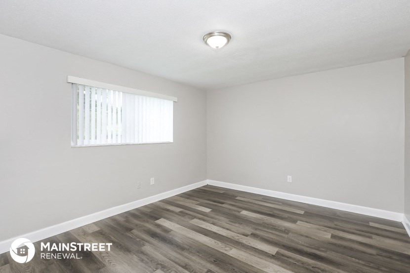 the spacious living room with wood flooring and a window