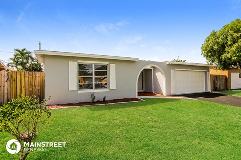 the front of a white house with a lawn and a driveway