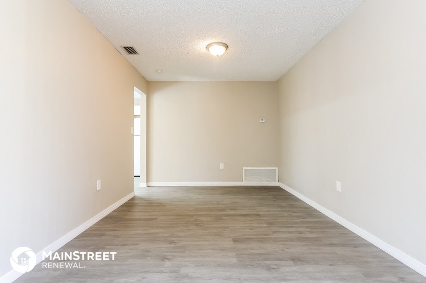 the spacious living room with white walls and wood flooring