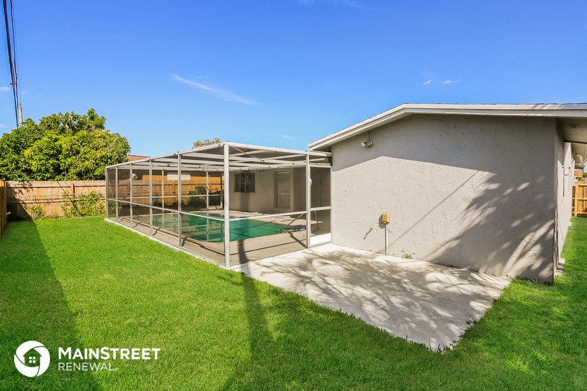 the backyard of a house with a pool and a screened in porch