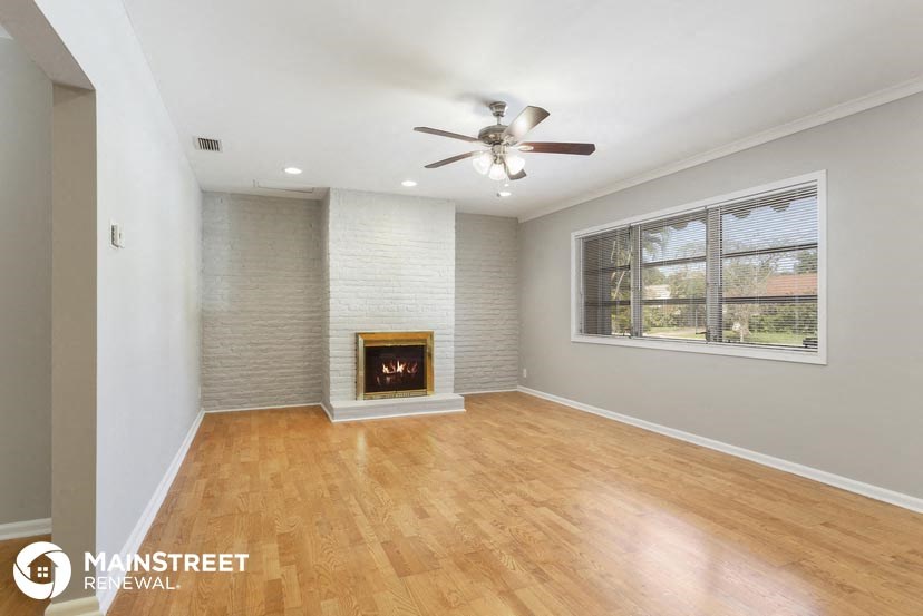 an empty living room with a ceiling fan and a fireplace