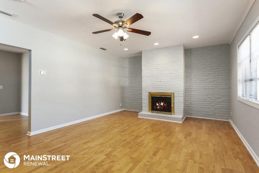 an empty living room with a fireplace and wooden floors