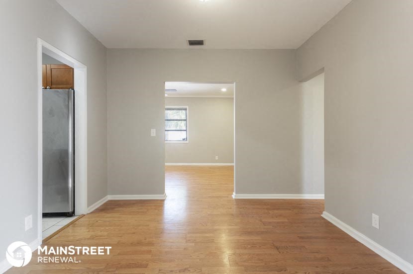 an empty living room with a refrigerator in it