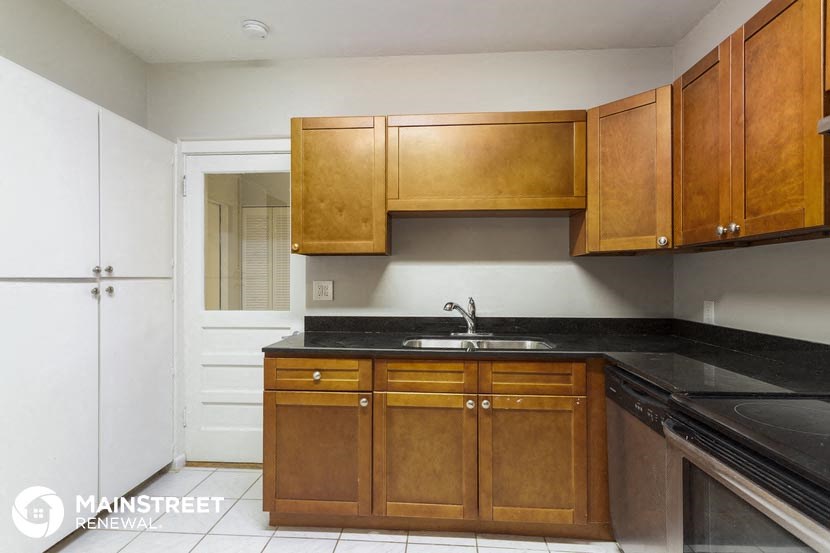 a kitchen with wooden cabinets and a black counter top